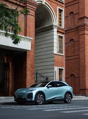 A light blue car parked on a city street next to a red brick building.