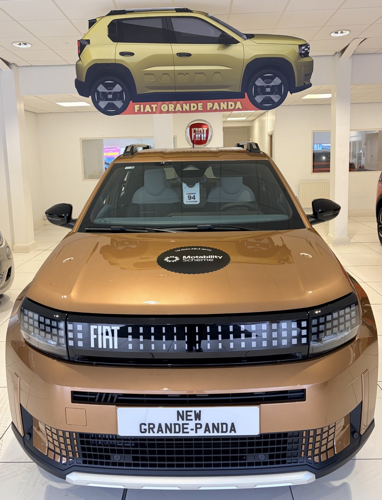 Fiat Grande Panda on display in a showroom, with model name visible on a hanging sign.