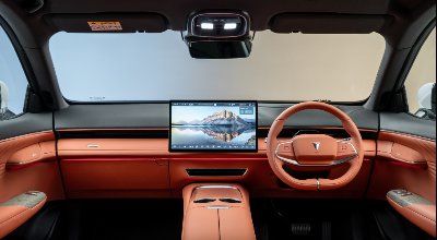 Car interior with orange upholstery, large central screen, and a steering wheel.