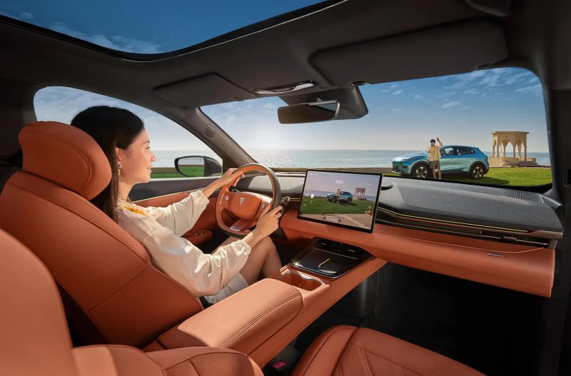 Woman drives a car with brown leather interior, ocean and person outside visible through windshield.