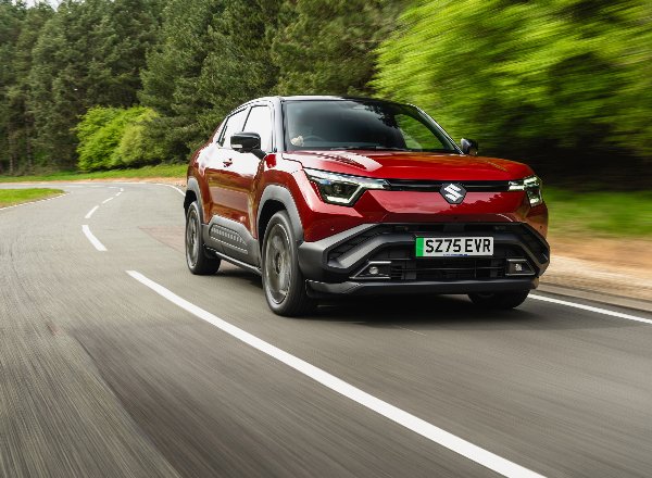 Red Suzuki e Vitara driving on a winding road.