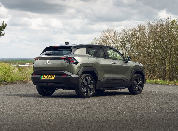 Suzuki e Vitara electric car parked on a road, rear side view.