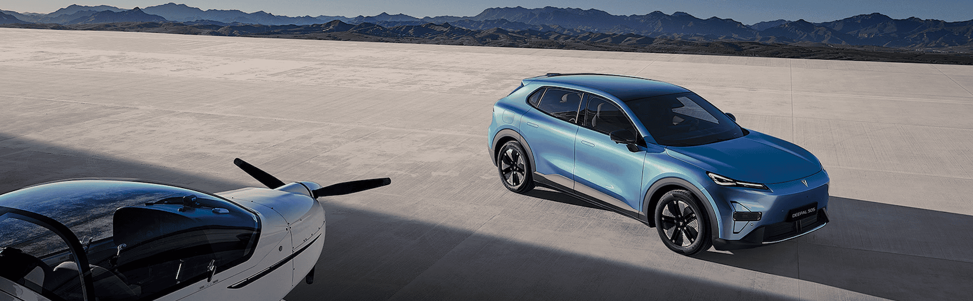 Blue SUV parked next to a small aeroplane on an expansive concrete surface.