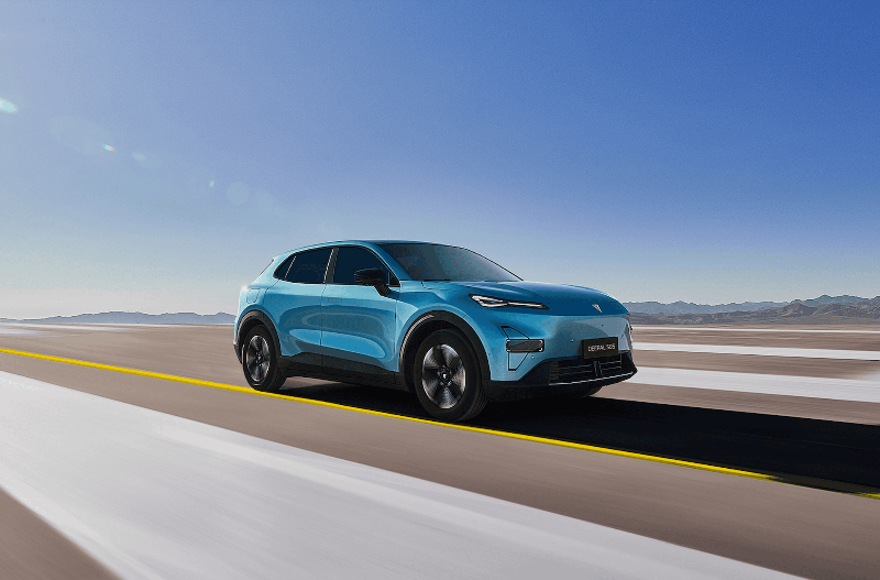 Blue car driving on a road under a clear sky.