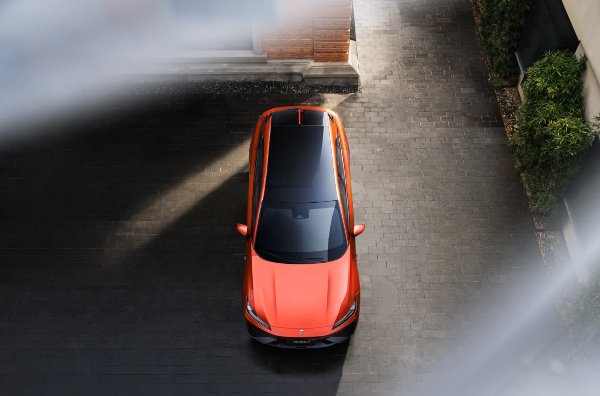 Top view of an orange car with a glass roof parked on a cobbled surface.