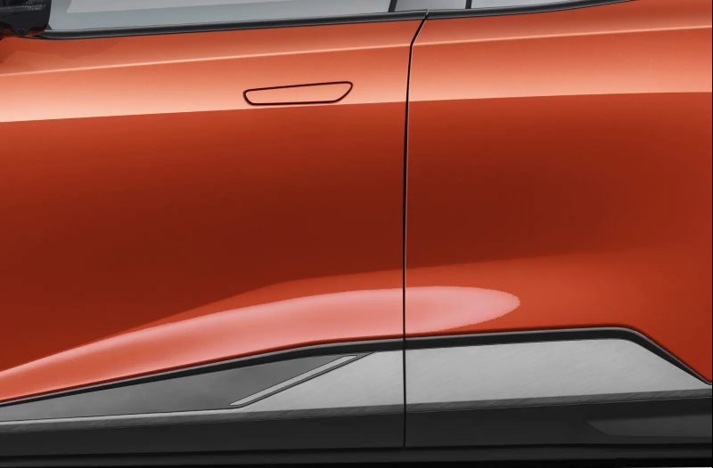 Close-up of a car door with an orange exterior, black underpanel, and hidden handle.