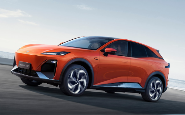 Orange electric SUV driving on a road, front side view.