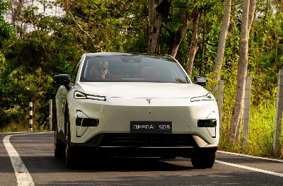 White Deepal S05 electric SUV driving on a road with greenery around.