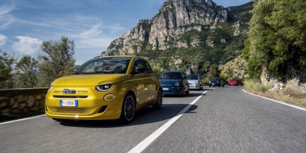 Yellow car leading a group of cars on a mountain road.